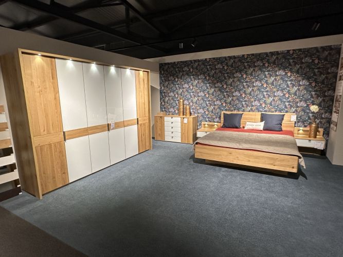Schlafzimmer mit großem beleuchtetem Kleiderschrank in Holz- und Lackkoptik bei Möbel Nachtsheim