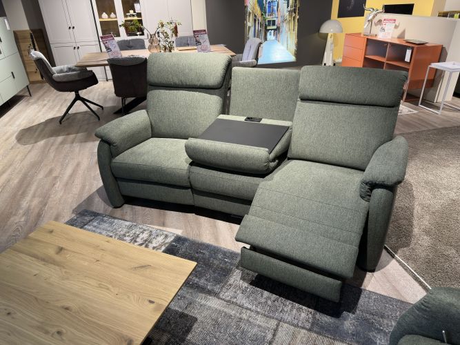 grünes Sofa mit umklappbarer Rückenlehne und hochfahrbarer Fußstütze in der Möbel Nachtsheim Polstermöbel-Ausstellung