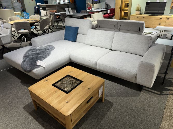 modernes, eckförmiges Stoffsofa in heller Farbe mit einem Massivholzcouchtisch