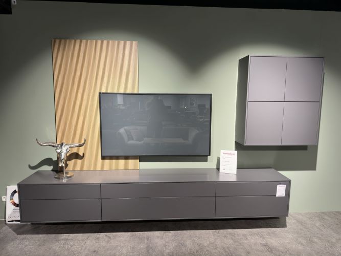 Graue TV-Möbel-Kombination in Lackoptik vor mintgrüner Wand in der Möbel Nachtsheim Ausstellung