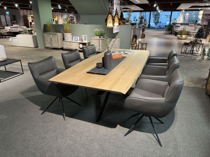 dunkle Armlehnstühle rund um einen Holz-Esszimmertisch in der Möbel Nachtsheim Ausstellung
